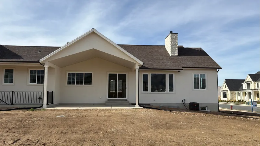Back of house featuring a chimney, a patio, basement entrance.