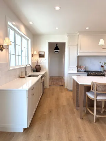 Kitchen featuring tasteful backsplash, quartz countertops, white oak cabinetry, a breakfast bar, and light wood finished floors