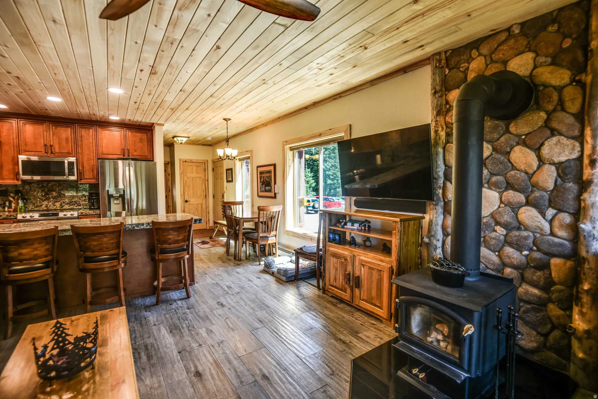 Living room with a wood stove, wooden ceiling, dark wood finished floors, recessed lighting, and a chandelier