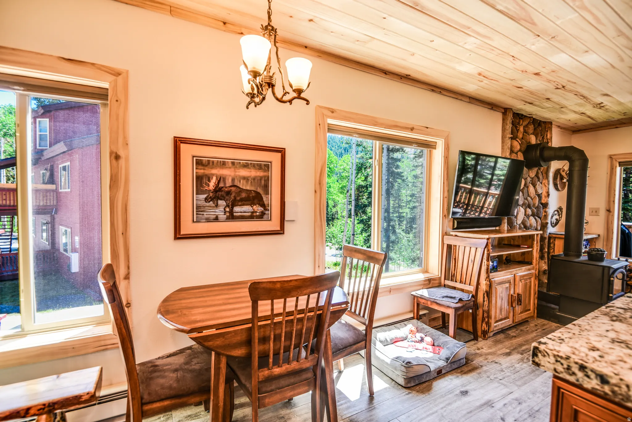 Dining space featuring a wood stove, plenty of natural light, wooden ceiling, hardwood / wood-style floors, and a chandelier