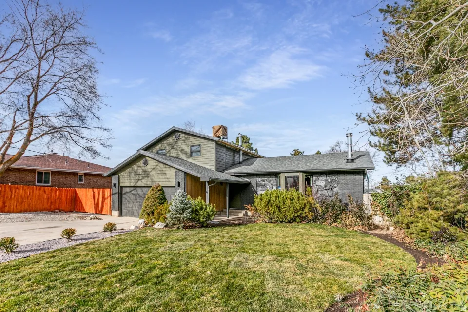 View of front facade featuring driveway, a 2 car garage, fenced yard, new roof, new siding with stone and  brick.