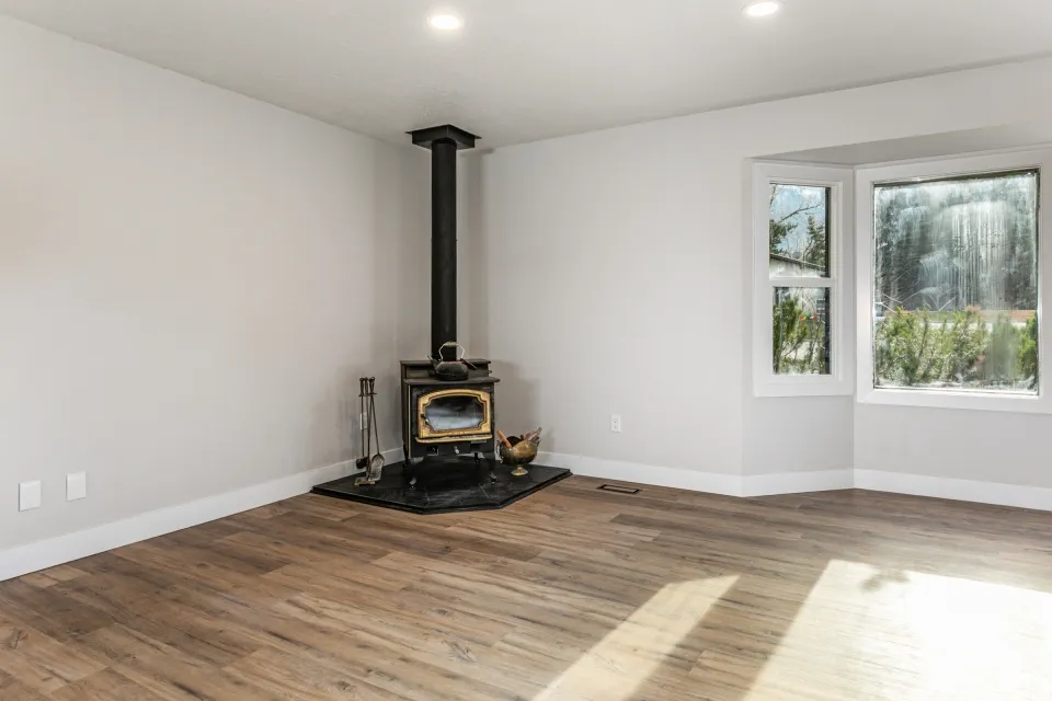 Living room featuring a wood stove, LVP floors, and recessed lighting with a bay window.