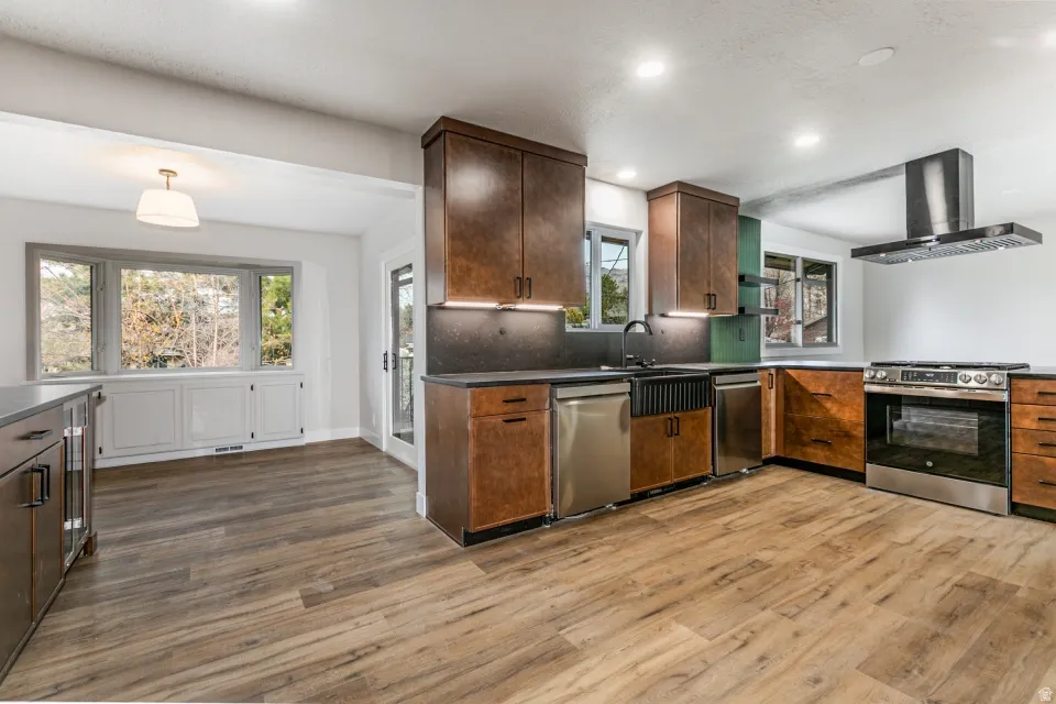 Kitchen with granite countertops, extractor fan, recessed lighting, stainless steel dishwasher, and a dining nook.