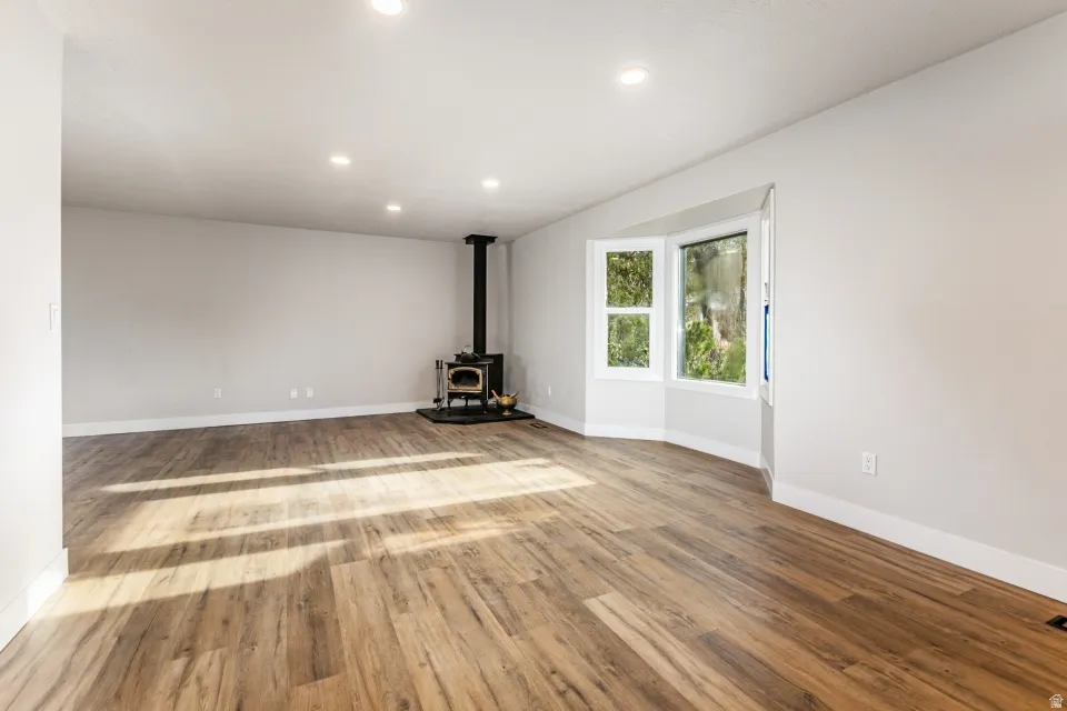 Living room featuring a wood stove, LVP floors, and recessed lighting with a bay window.