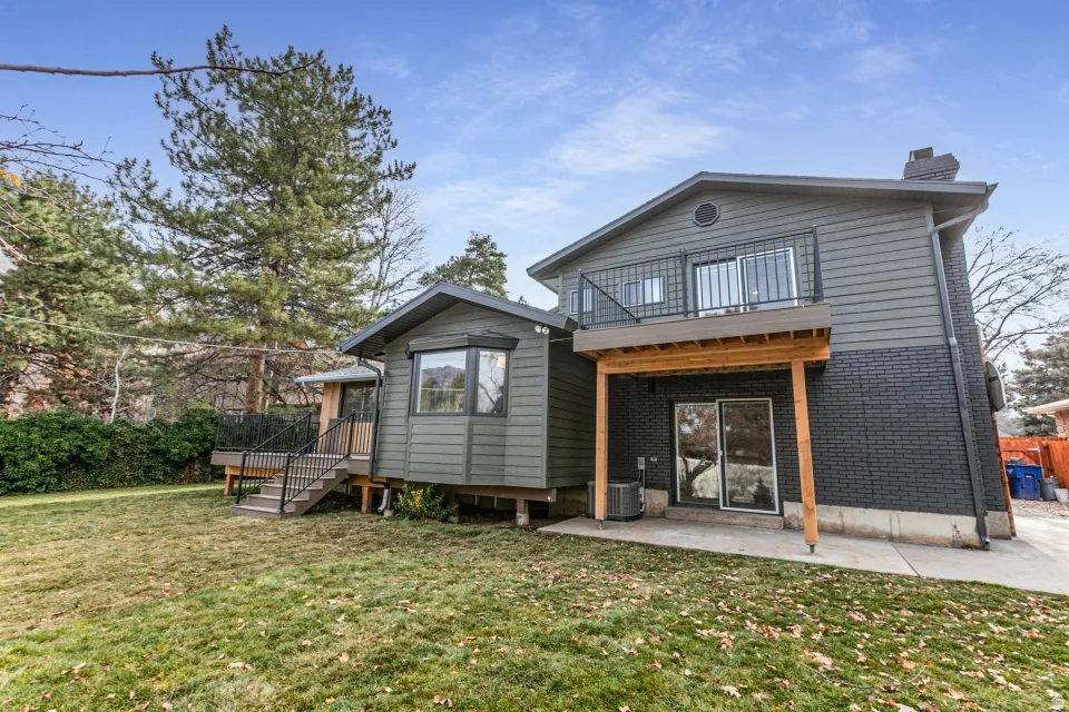 Rear view of house with a yard, a chimney, a patio, brick siding, and stairs