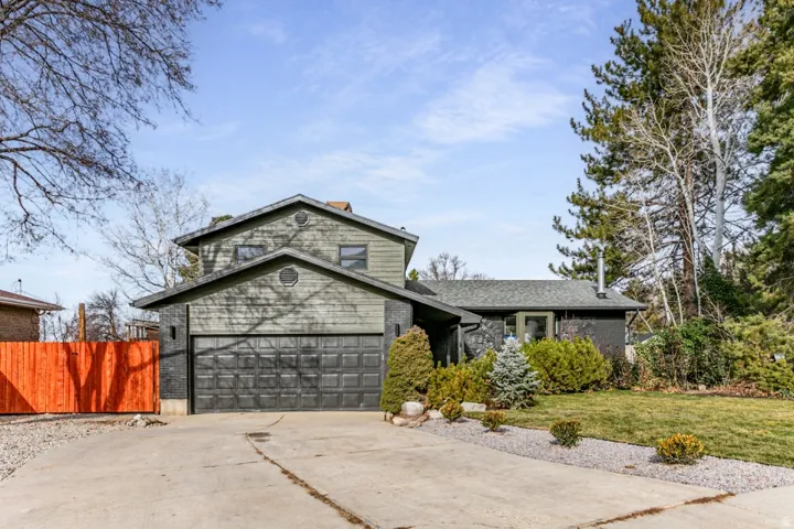 View of front facade featuring driveway, a 2 car garage, fenced yard, new roof, new siding with stone and  brick.