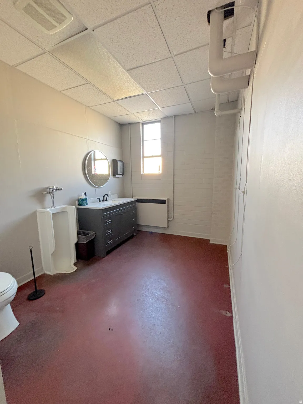 Bathroom with a drop ceiling, vanity, and finished concrete floors