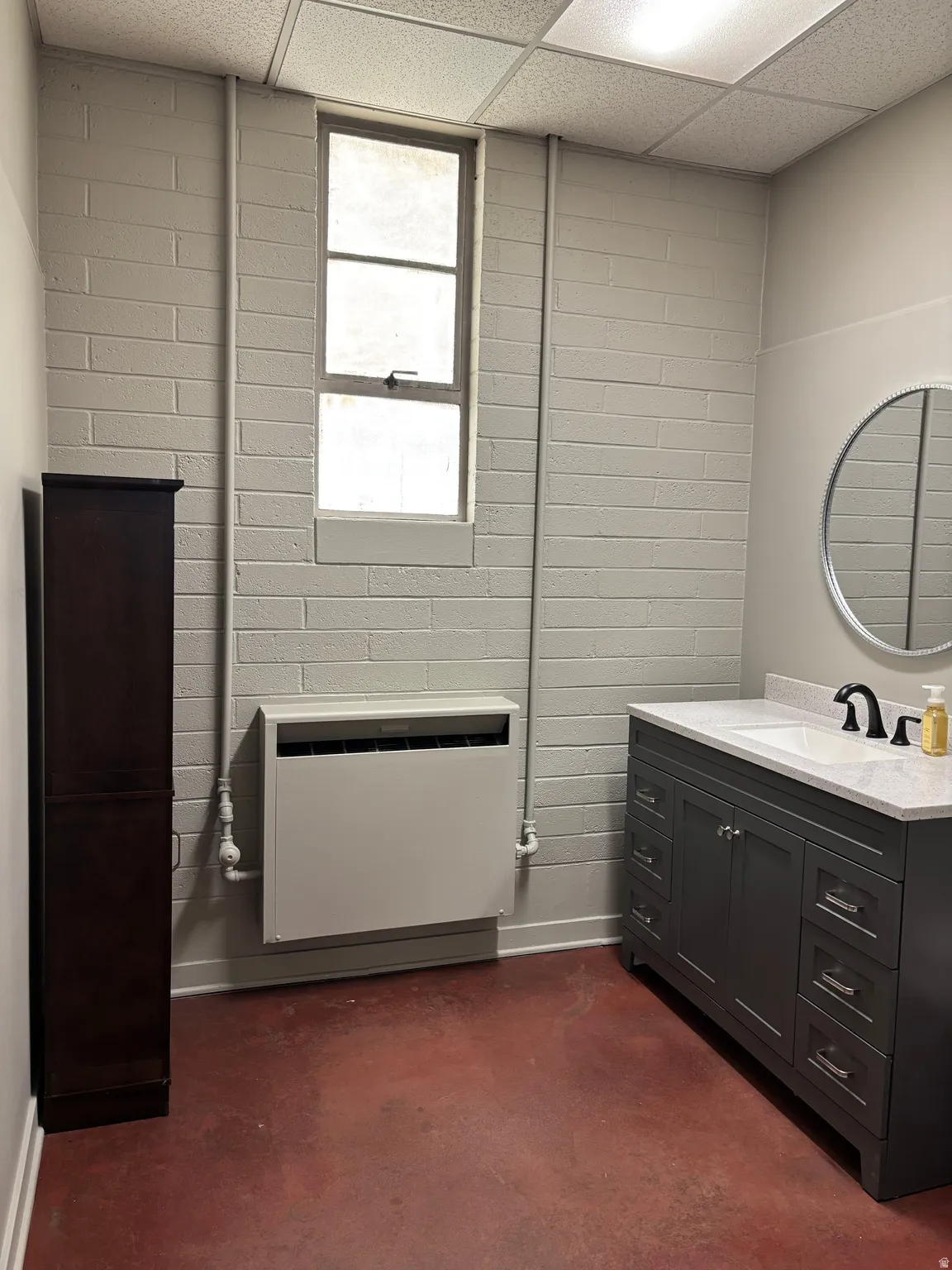 Bathroom featuring vanity, concrete floors, heating unit, and a paneled ceiling