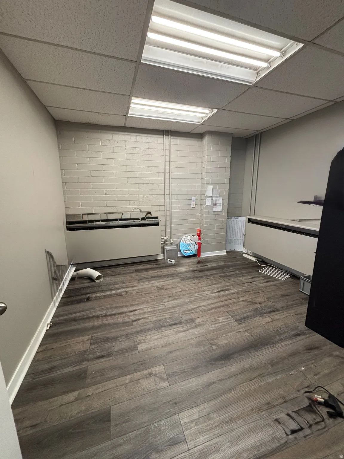 Empty room featuring a paneled ceiling and dark wood-type flooring