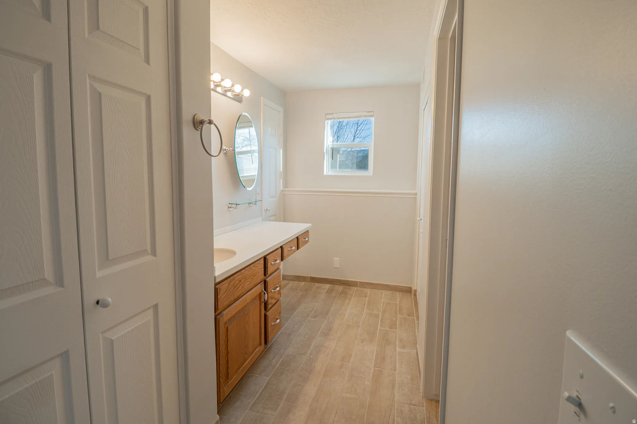 Bathroom featuring vanity, light wood-style floors, and a closet
