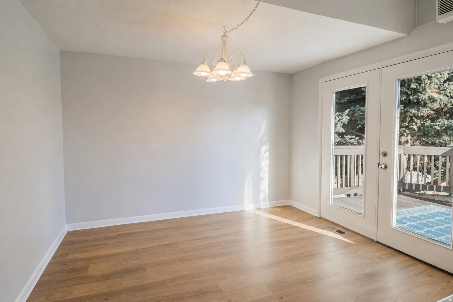 Spacious room featuring wood-finish flooring, light gray walls, and white baseboards