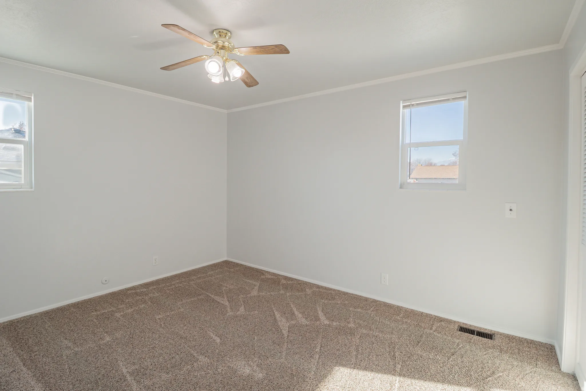 Spare room with ornamental molding, carpet floors, and ceiling fan