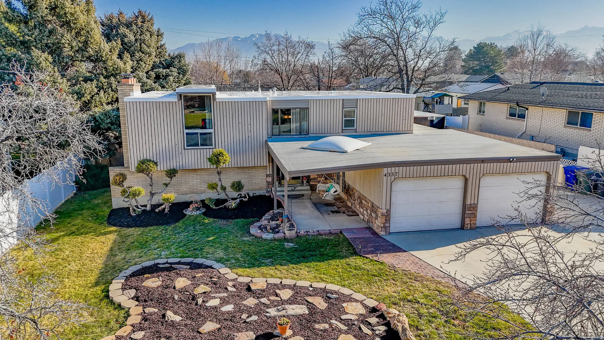 Mid-century inspired home featuring concrete driveway, a mountain view, and a chimney