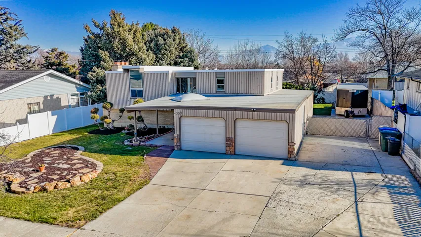 View of front of property with driveway, a garage, and a gate