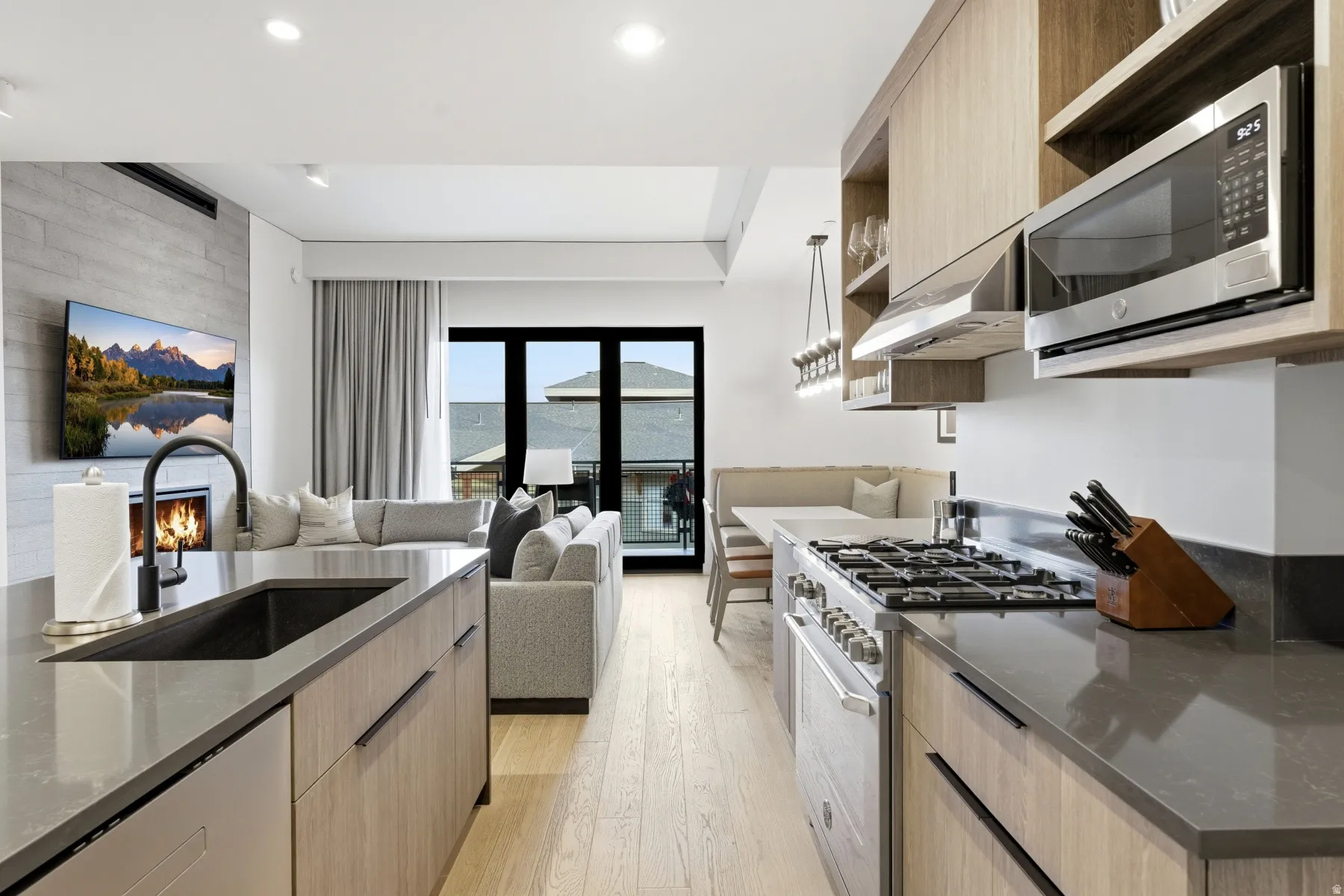 Kitchen with open shelves, stainless steel appliances, light brown cabinetry, and dark stone countertops