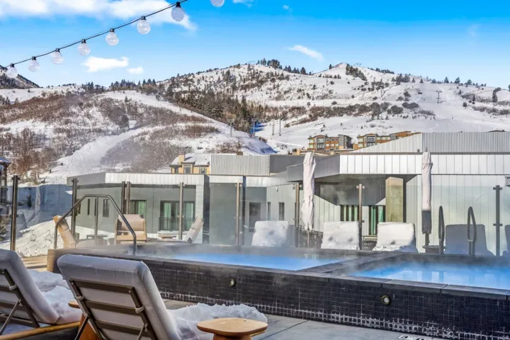 Snow covered house with a patio area, a mountain view, and an infinity pool