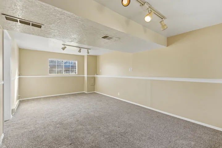 Carpeted empty room with track lighting and a textured ceiling