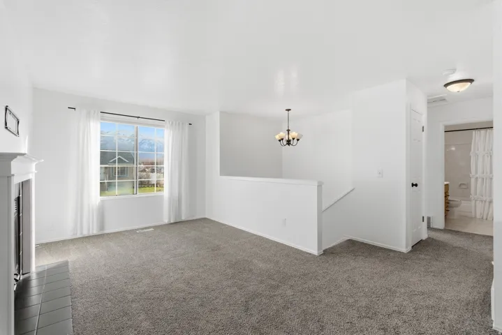 Unfurnished living room featuring carpet floors, a chandelier, and a fireplace with flush hearth