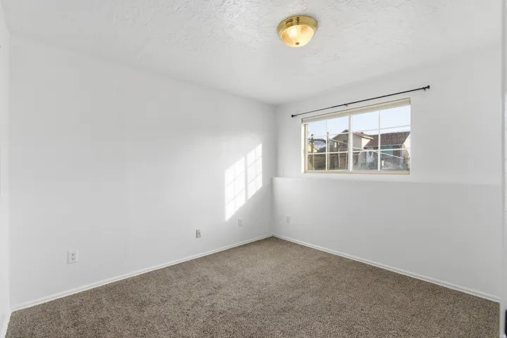 Carpeted empty room featuring a textured ceiling and baseboards