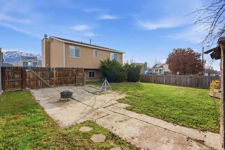 Rear view of house with a patio, a fenced backyard, a fire pit, and a gate