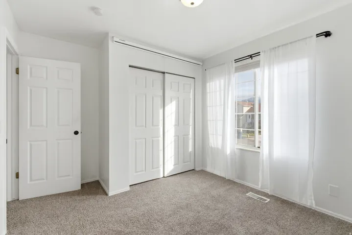 Bedroom with light colored carpet and a closet