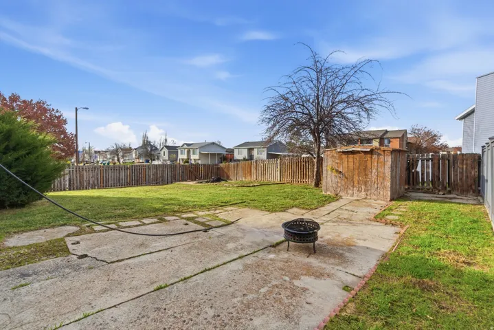 Fenced backyard with an outdoor fire pit, a patio, and a residential view