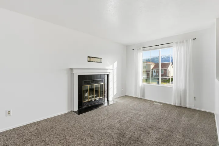 Unfurnished living room featuring carpet floors, a fireplace, and a textured ceiling