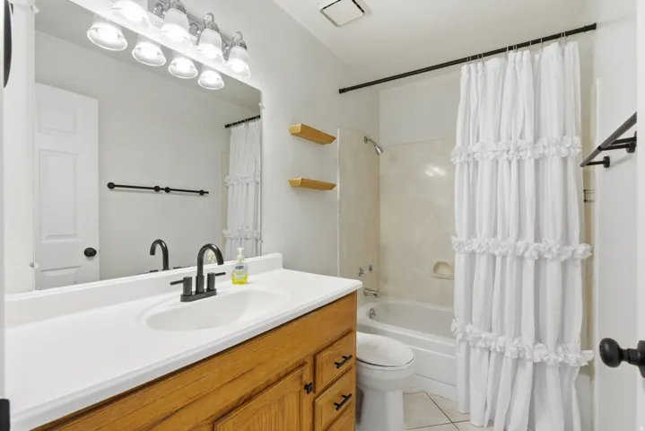 Full bathroom with vanity, shower / tub combo with curtain, and light tile patterned flooring