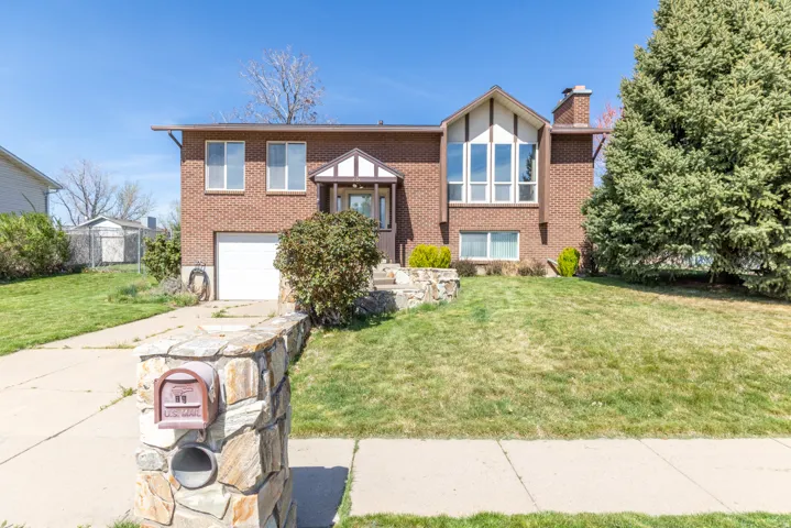 English style home featuring a front lawn, a garage, a chimney, brick siding, and concrete driveway