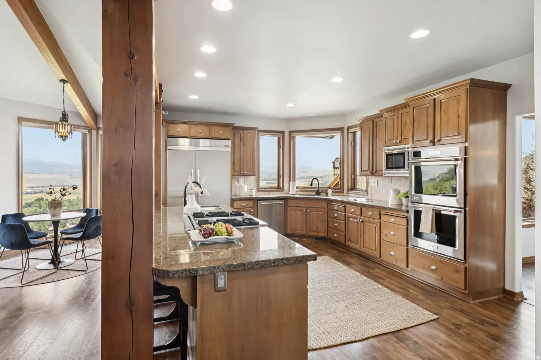 Kitchen with built in appliances, brown cabinets, a kitchen bar, dark wood finished floors, and dark stone countertops