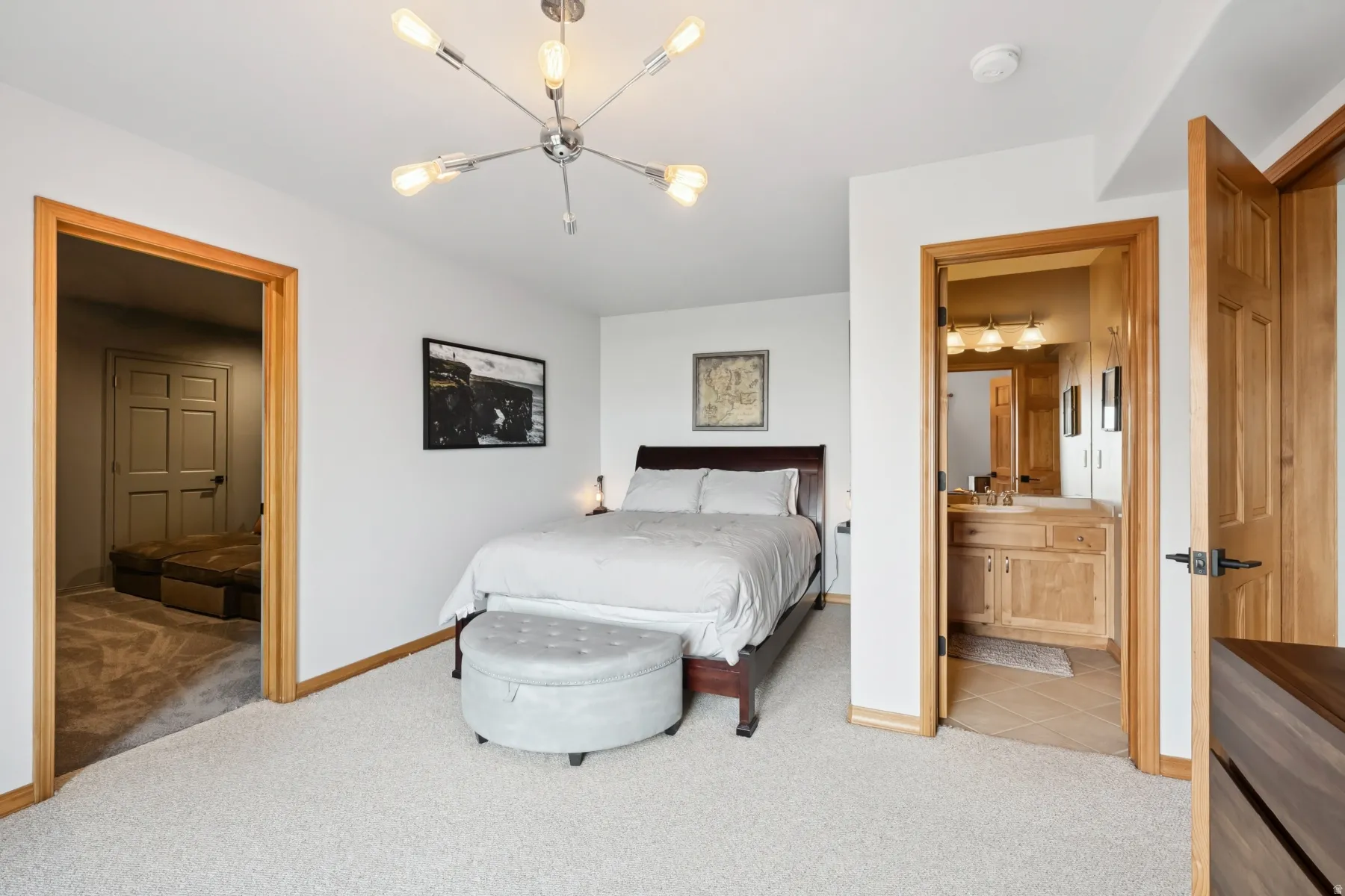 Bedroom featuring light colored carpet, connected bathroom, and a chandelier