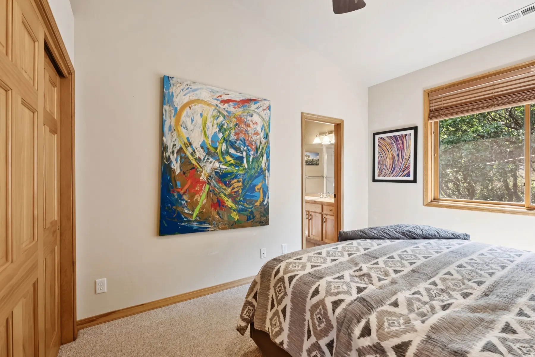 Carpeted bedroom with connected bathroom and a ceiling fan