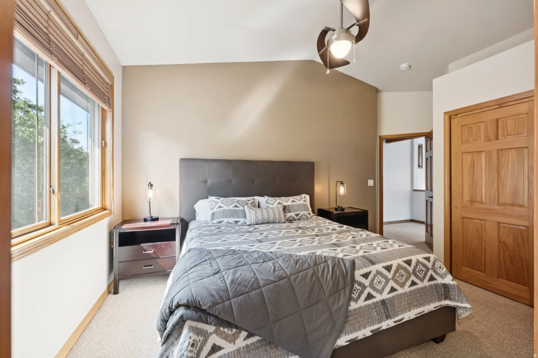 Bedroom with ceiling fan, light carpet, and lofted ceiling