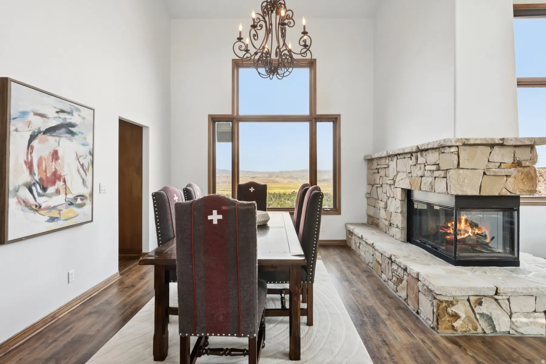 Dining room featuring a towering ceiling, a chandelier, wood finished floors, and a fireplace