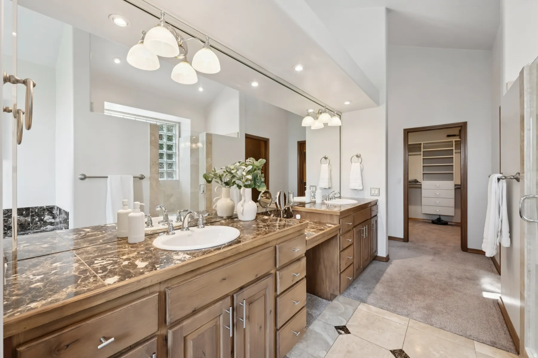Bathroom with a stall shower, light carpet, two vanities, double vanity, and a walk in closet