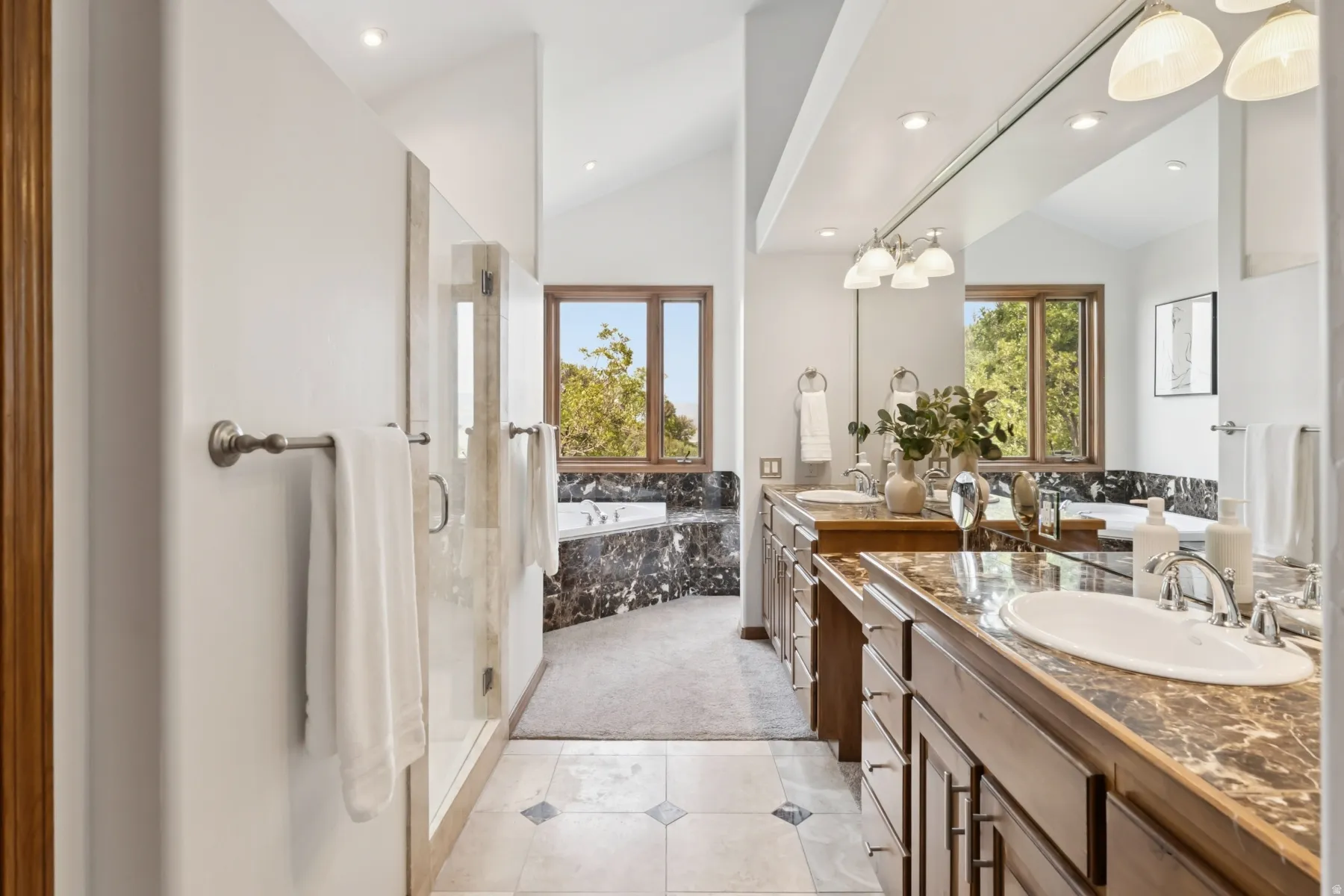 Full bathroom with vaulted ceiling, a bath, double vanity, healthy amount of natural light, and a stall shower