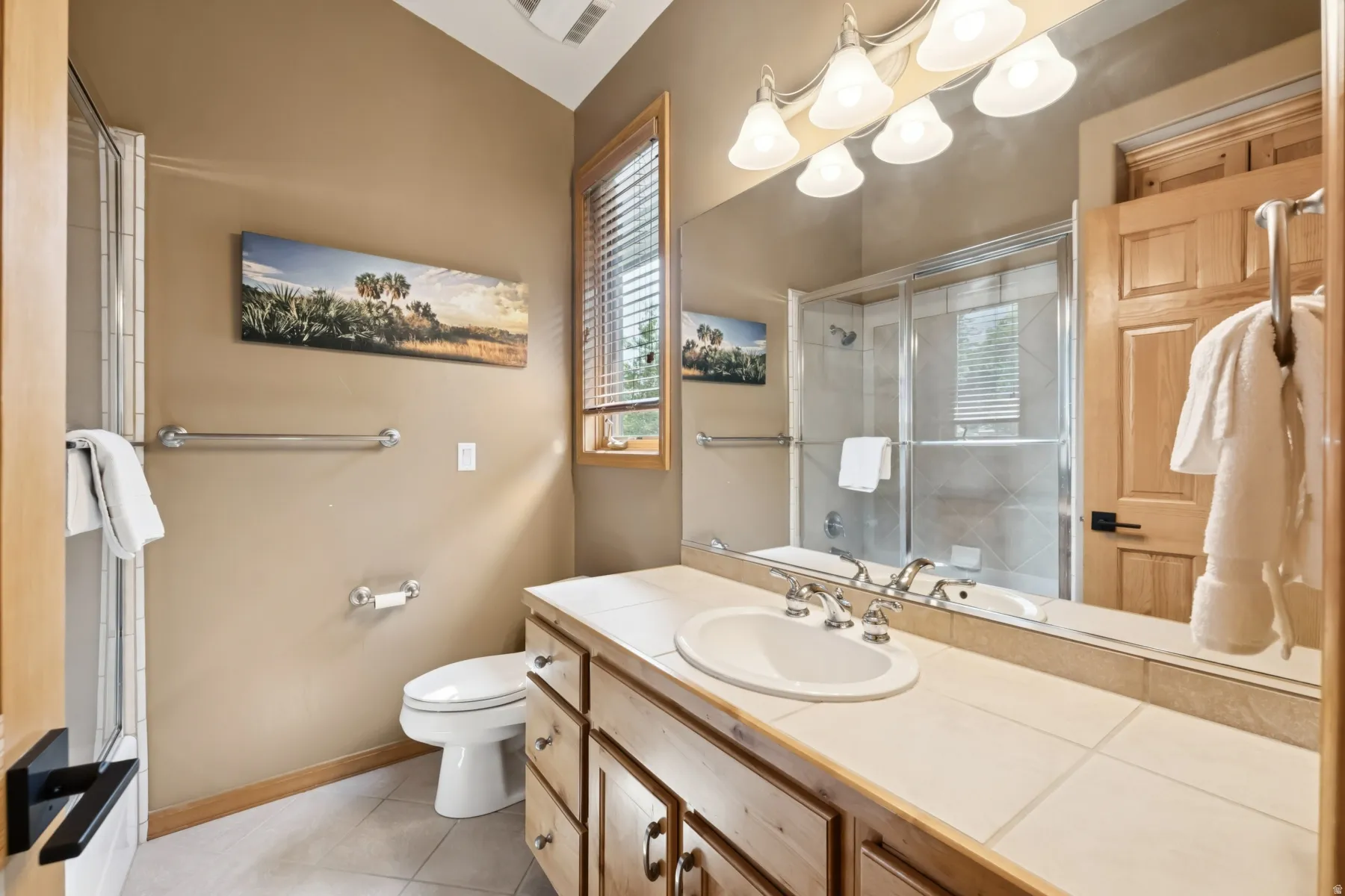 Full bath with a shower with door, vanity, and light tile patterned flooring