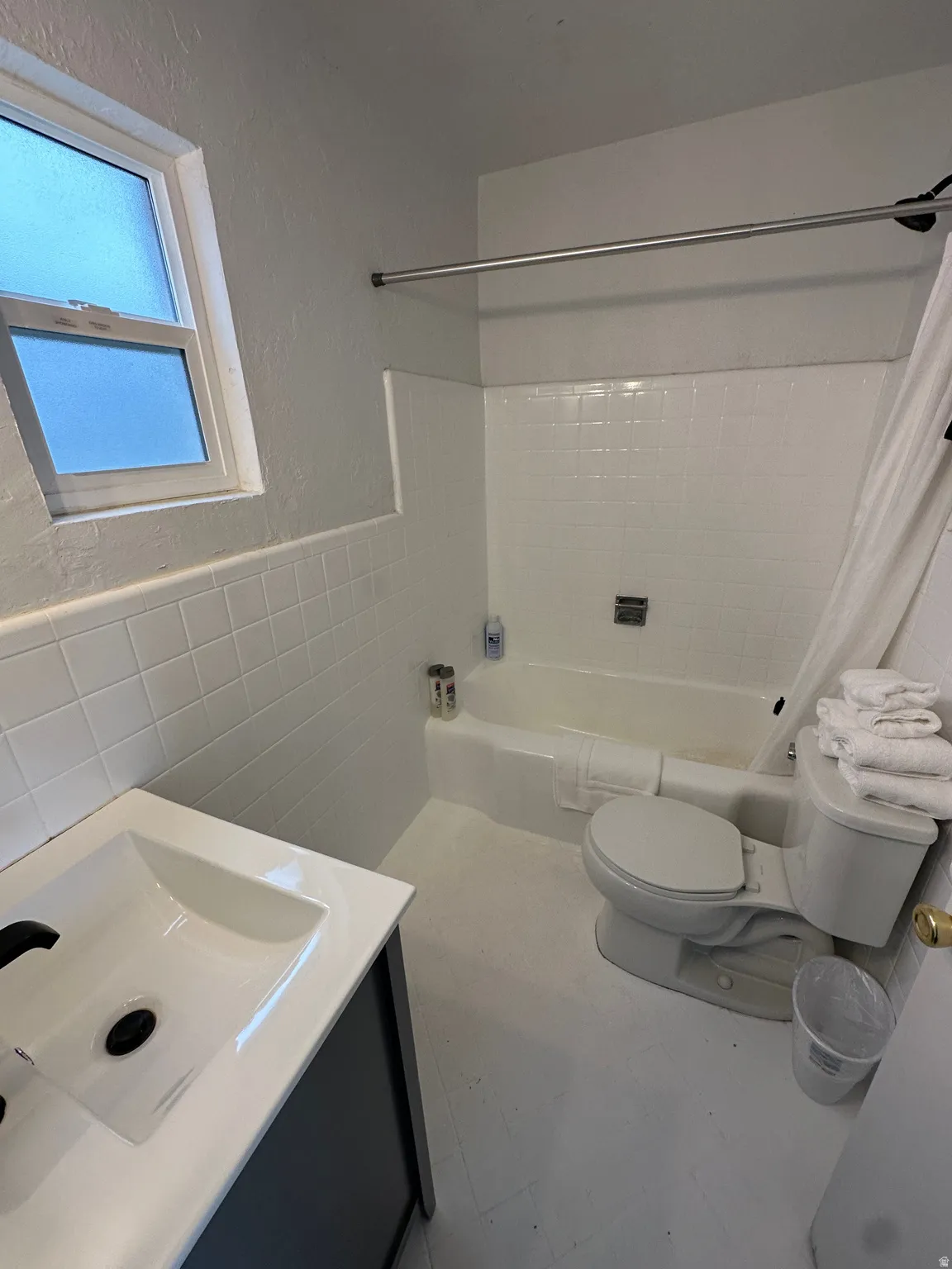 Full bath with tile walls, vanity, wainscoting, and shower / bath combination with curtain