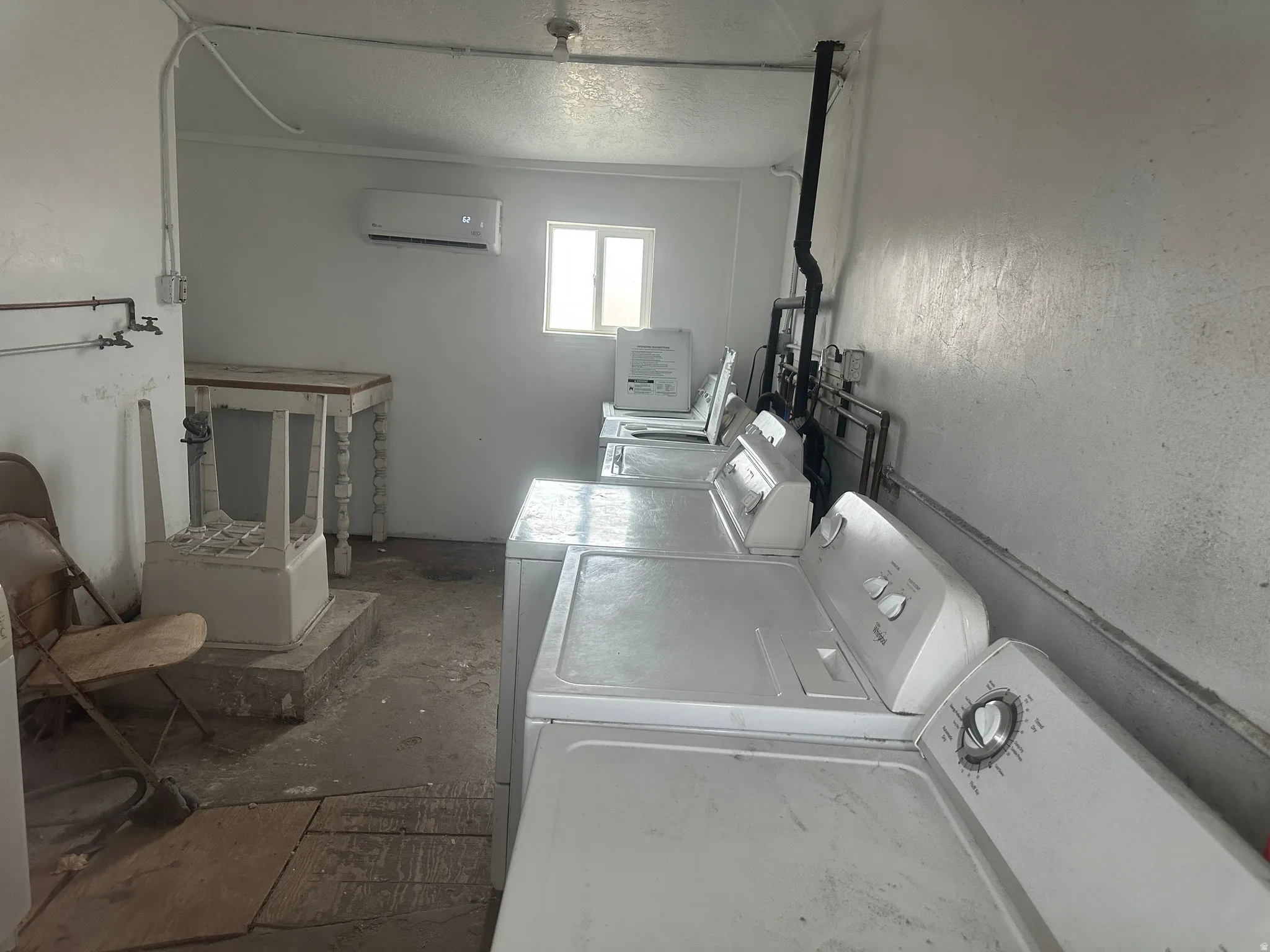 Laundry area featuring washer and clothes dryer, a wall mounted AC, and a textured ceiling