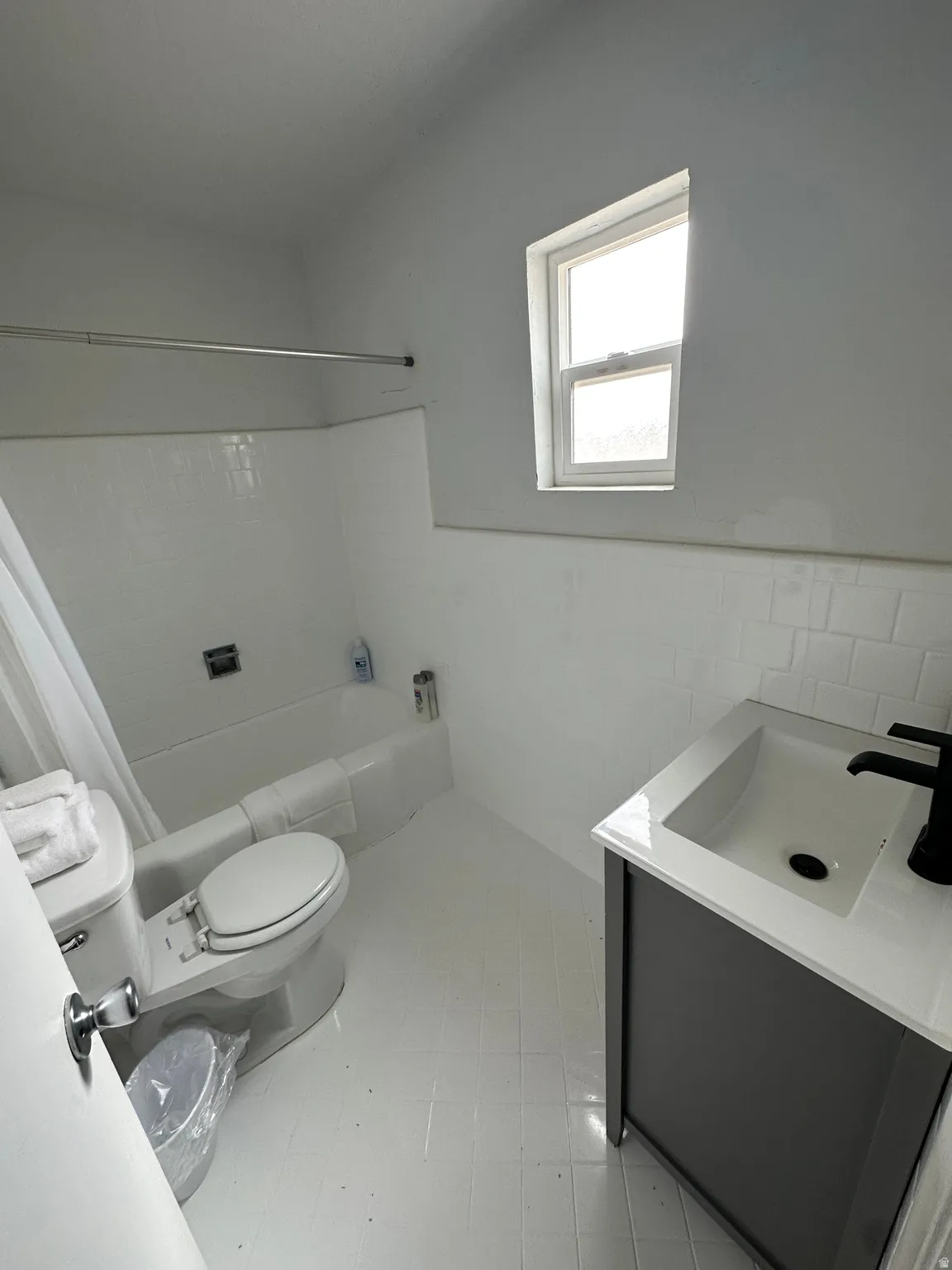 Full bathroom with vanity, tile walls, shower / bathtub combination with curtain, and a wainscoted wall