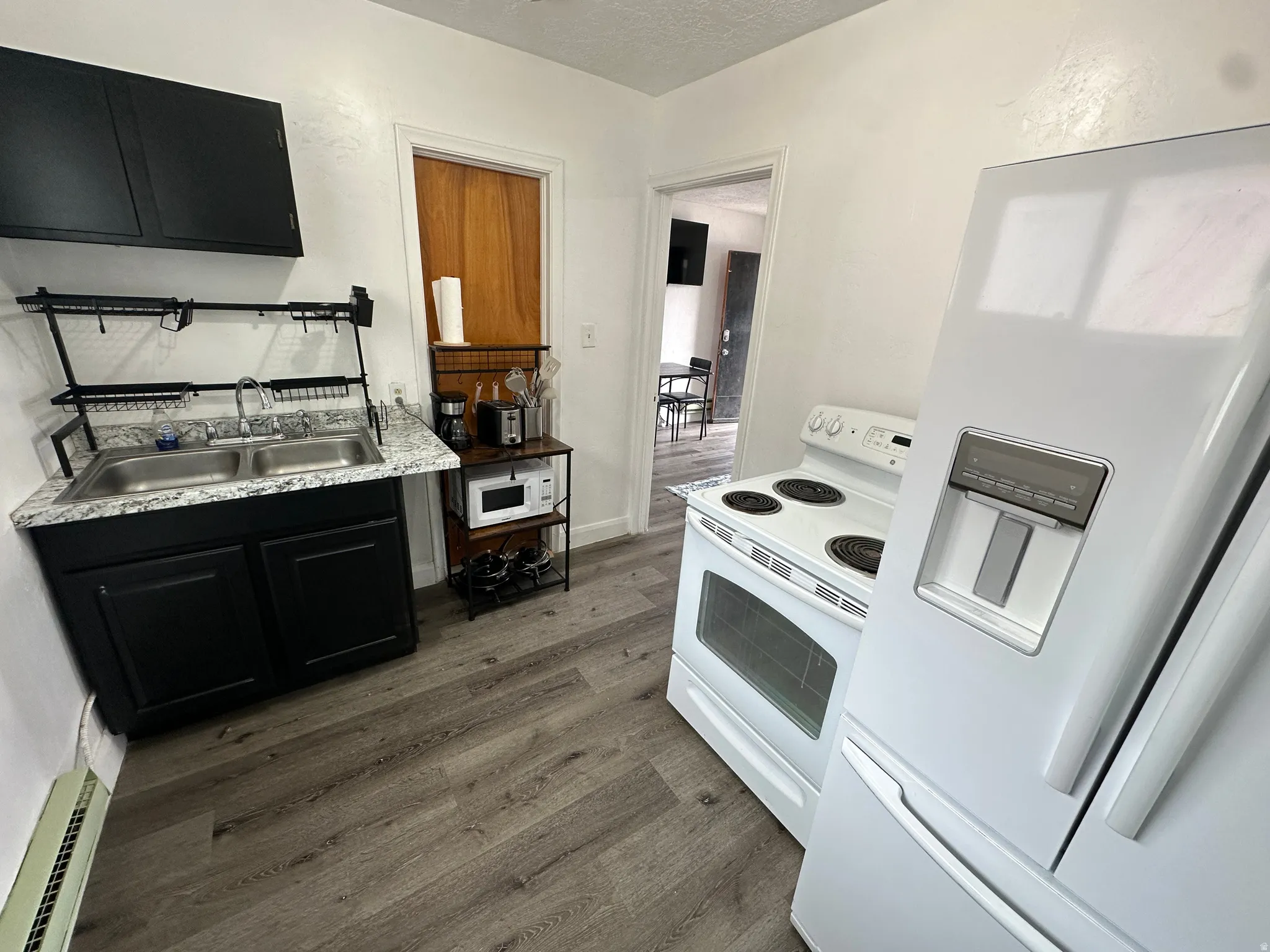 Kitchen with white appliances, dark cabinetry, light countertops, and dark wood finished floors