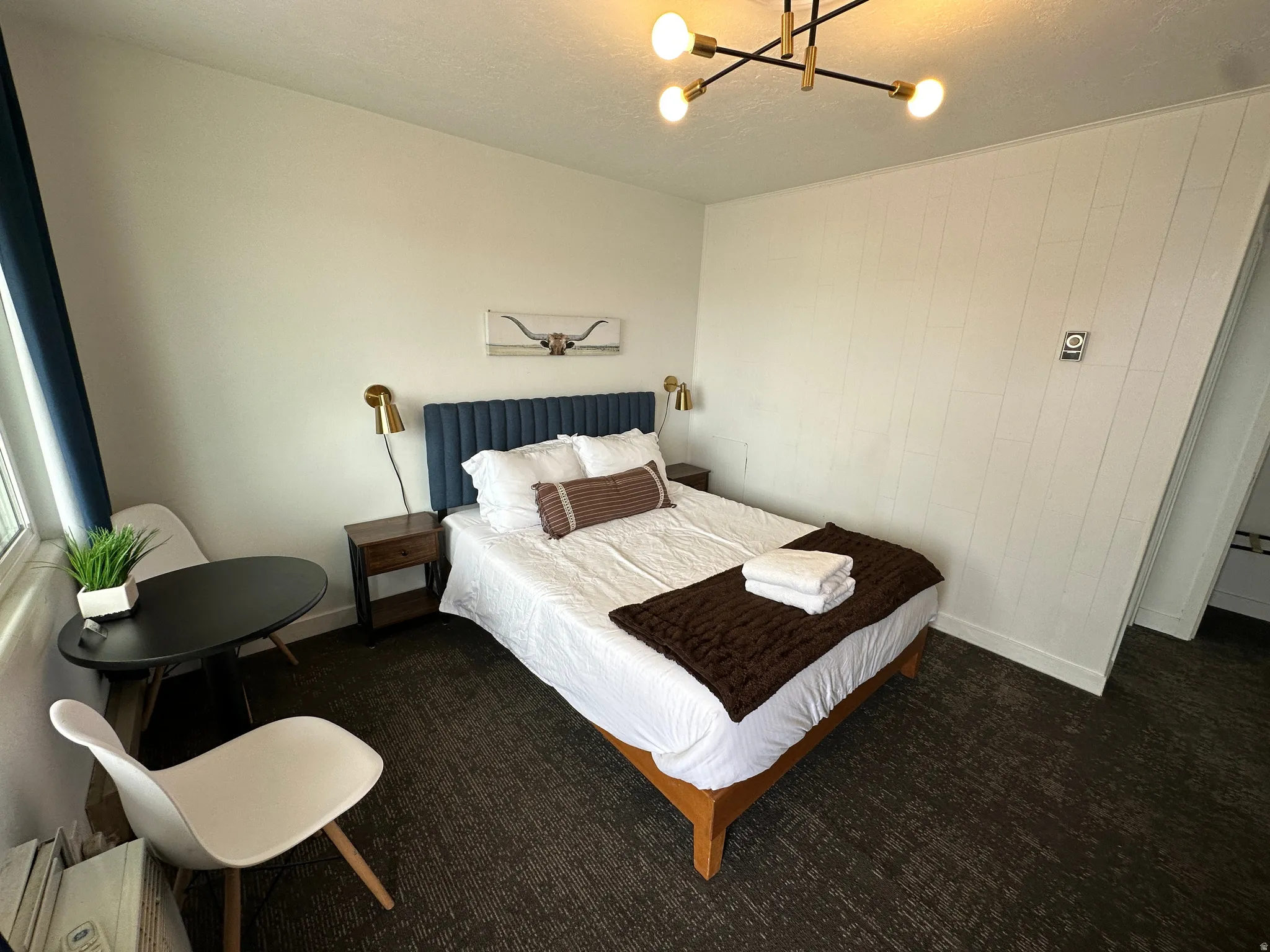 Carpeted bedroom featuring a chandelier and a baseboard heating unit