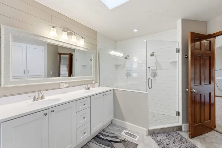 Bathroom with double vanity, a shower stall, and a textured ceiling