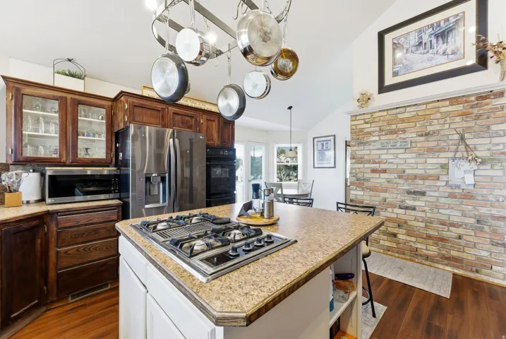 Kitchen featuring light countertops, a kitchen island, white cabinets, stainless steel appliances, and vaulted ceiling