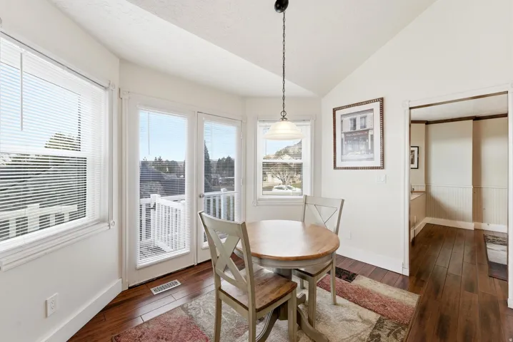 Dining area with vaulted ceiling, dark wood-style flooring, and a textured ceiling