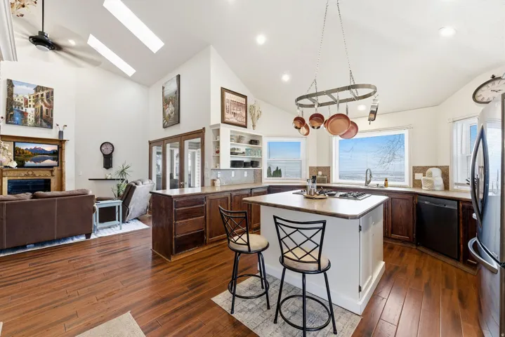 Kitchen featuring a fireplace, freestanding refrigerator, open floor plan, a skylight, and dishwasher