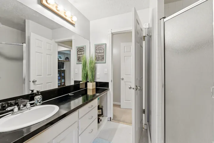 Full bathroom with vanity, a stall shower, a textured ceiling, and light tile patterned floors