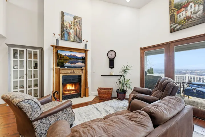 Living area with a towering ceiling, wood finished floors, and a glass covered fireplace