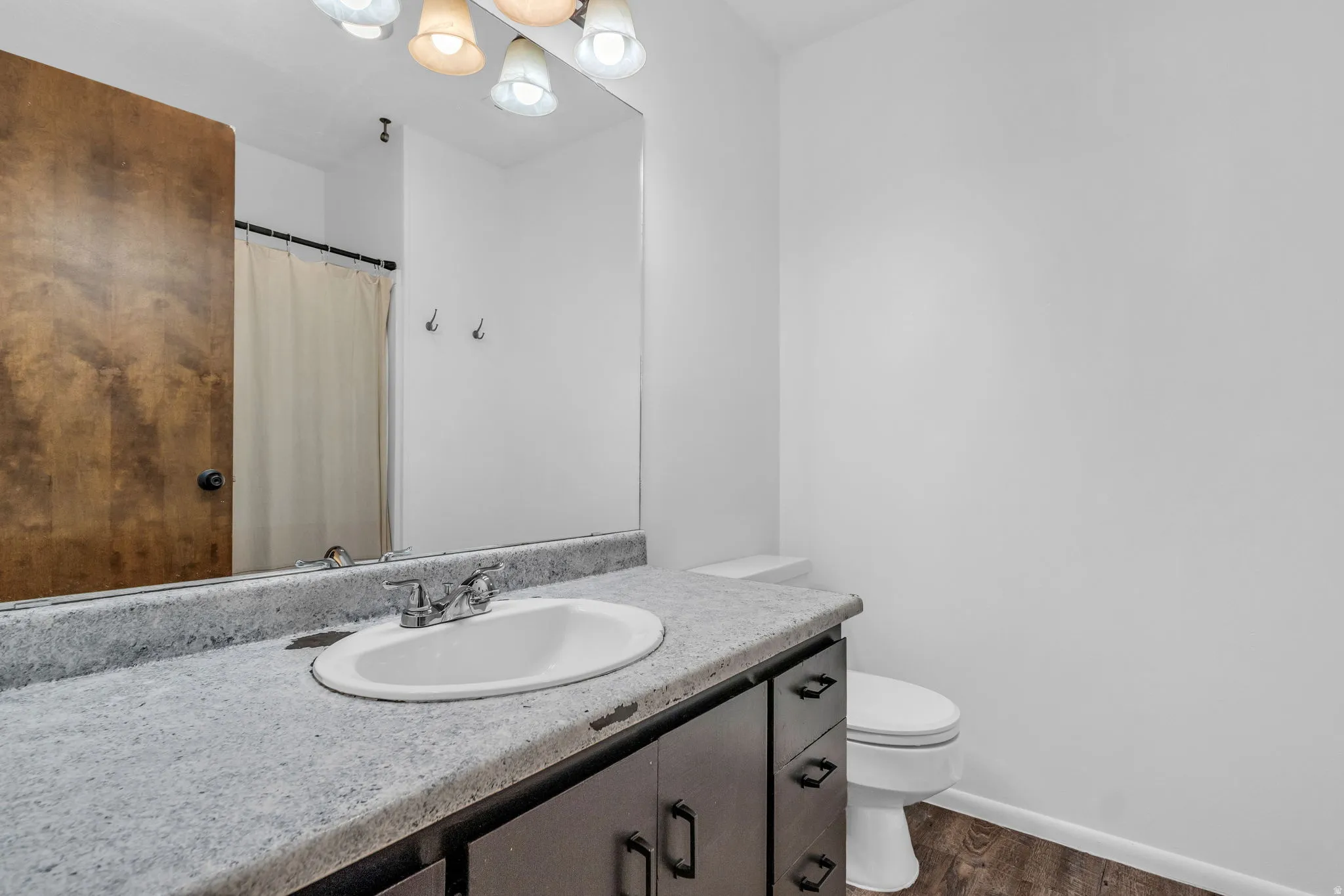 Bathroom with a shower with curtain, vanity, and dark wood-style flooring