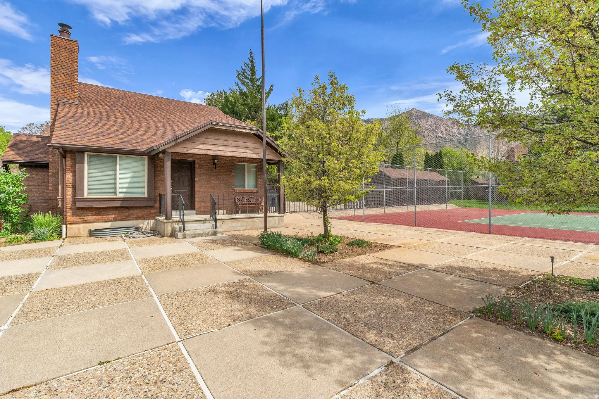 View of front facade featuring a porch, brick siding, roof with shingles, a chimney, and a mountain view